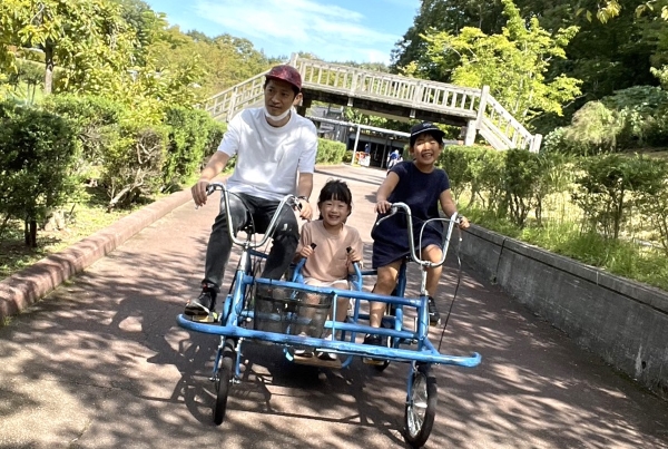 大人1人と子ども2人が自転車をこいでいる