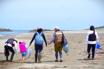 砂浜に大人4人と子供1にが歩いている